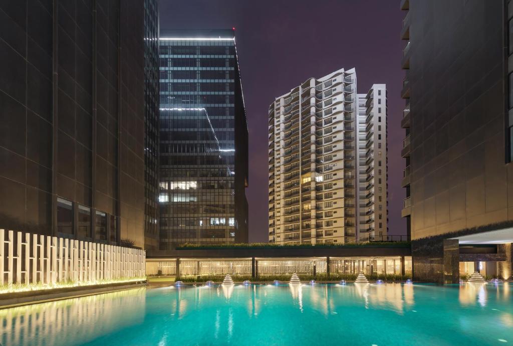 a pool in a city at night with tall buildings at Kantharyar Serviced Apartment in Yangon