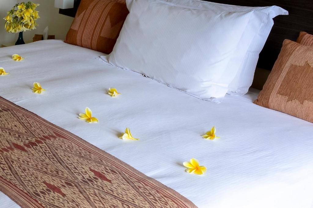 a bed with yellow flowers on top of it at Villa Karingal in Senggigi