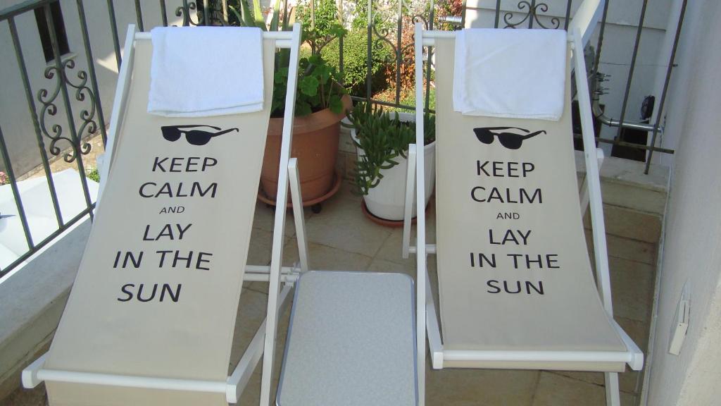 una señal que dice mantener la calma y acostarse al sol junto a dos sillas en Sole Mio, en Milina
