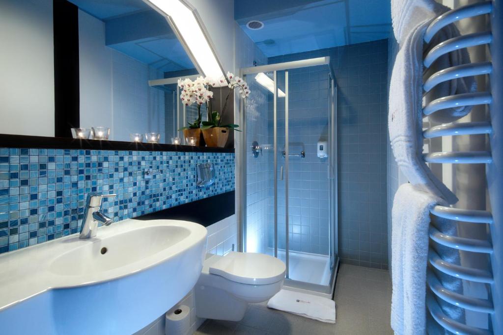 a blue bathroom with a sink and a toilet at Hotton Hotel in Gdynia