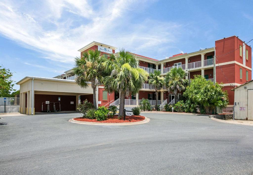 un gran edificio rojo con palmeras en un aparcamiento en Water Street Hotel & Marina, Ascend Hotel Collection, en Apalachicola
