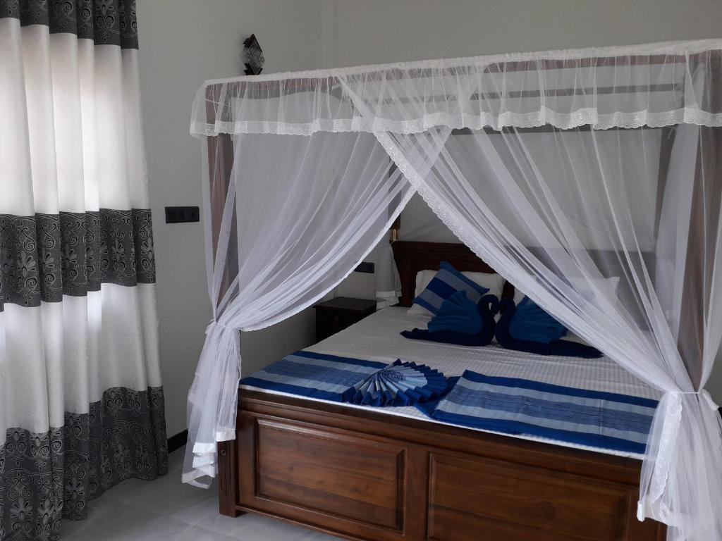 a bedroom with a canopy bed with blue pillows at The Wave's Guest House in Mirissa