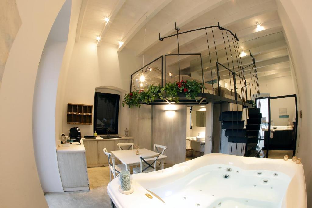 a bathroom with a tub and a table and a kitchen at Sebèl Luxury Rooms in Barletta