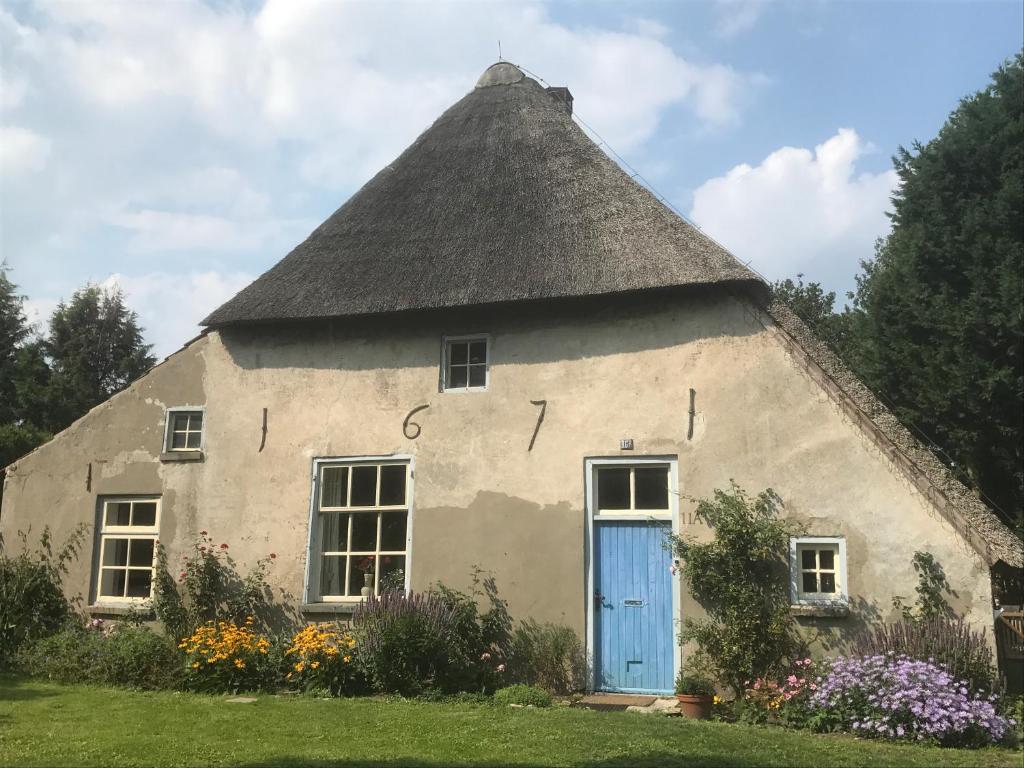a thatch roofed cottage with a blue door at B&B van Beijden in Overasselt