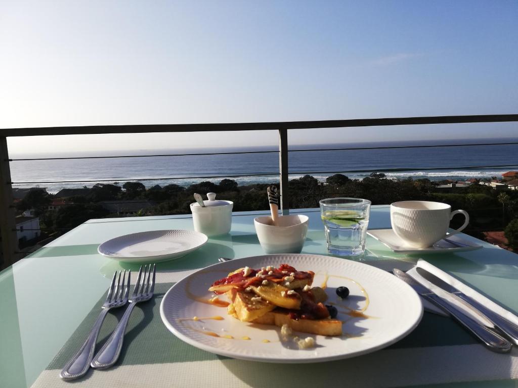 einen Teller mit Lebensmitteln auf einem Tisch mit Meerblick in der Unterkunft Ocean Vista Boutique Guest House in Durban