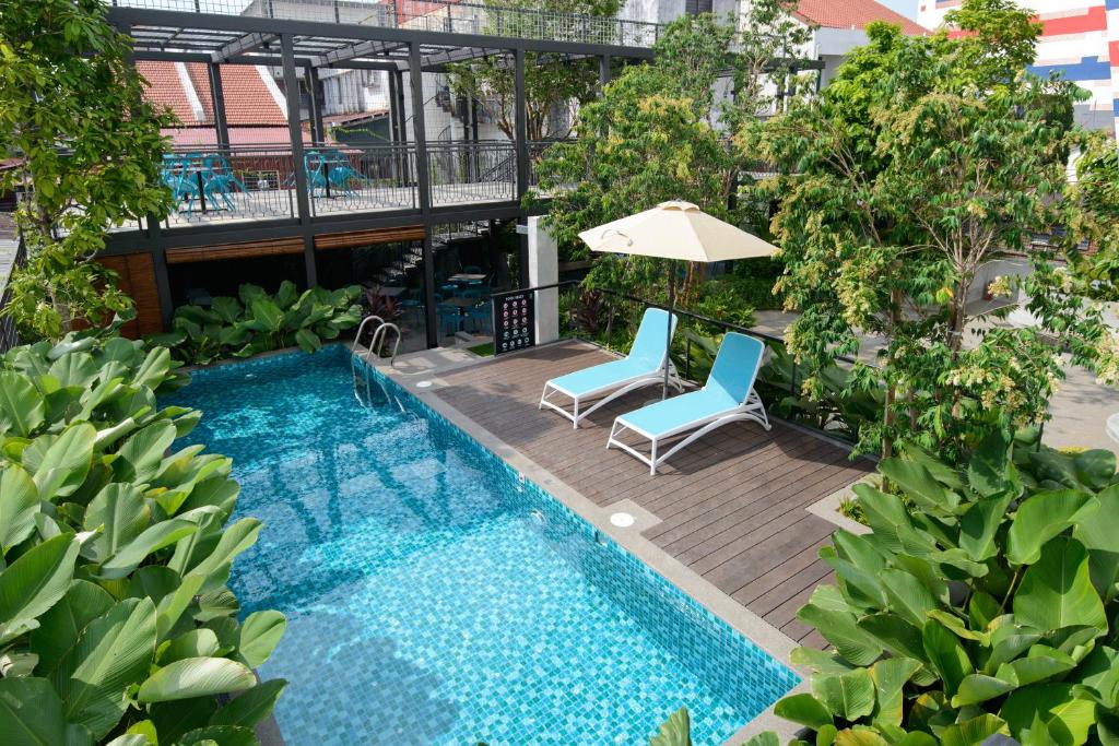 een uitzicht op een zwembad met 2 stoelen en een parasol bij SAVV HOTEL in George Town