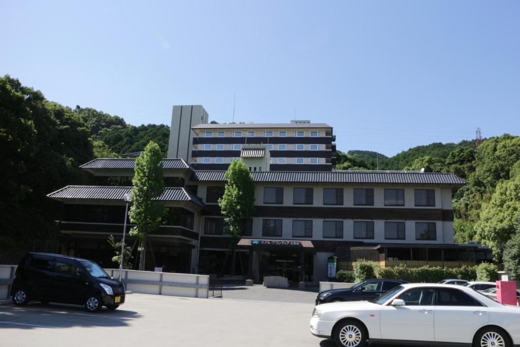 a white car parked in a parking lot in front of a building at Route Inn Grantia Dazaifu in Dazaifu