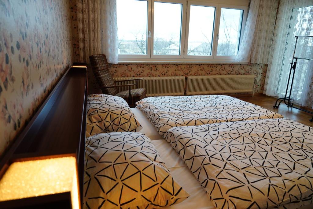 een slaapkamer met 2 bedden, een stoel en ramen bij Pension Sonnenblume in Donnerskirchen