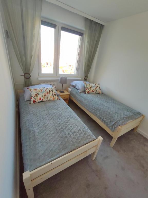 two beds in a room with two windows at Mieszkanie z dobrą energią in Giżycko