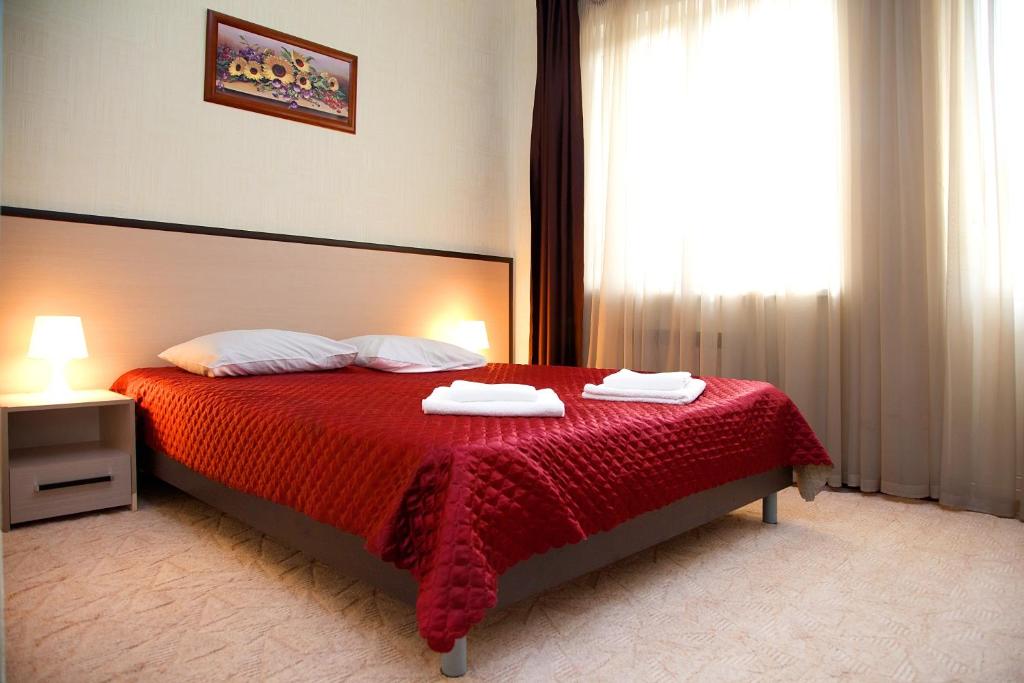 a bedroom with a bed with a red blanket and a window at Utomlyonnye Solntsem Hotel in Krasnaya Polyana