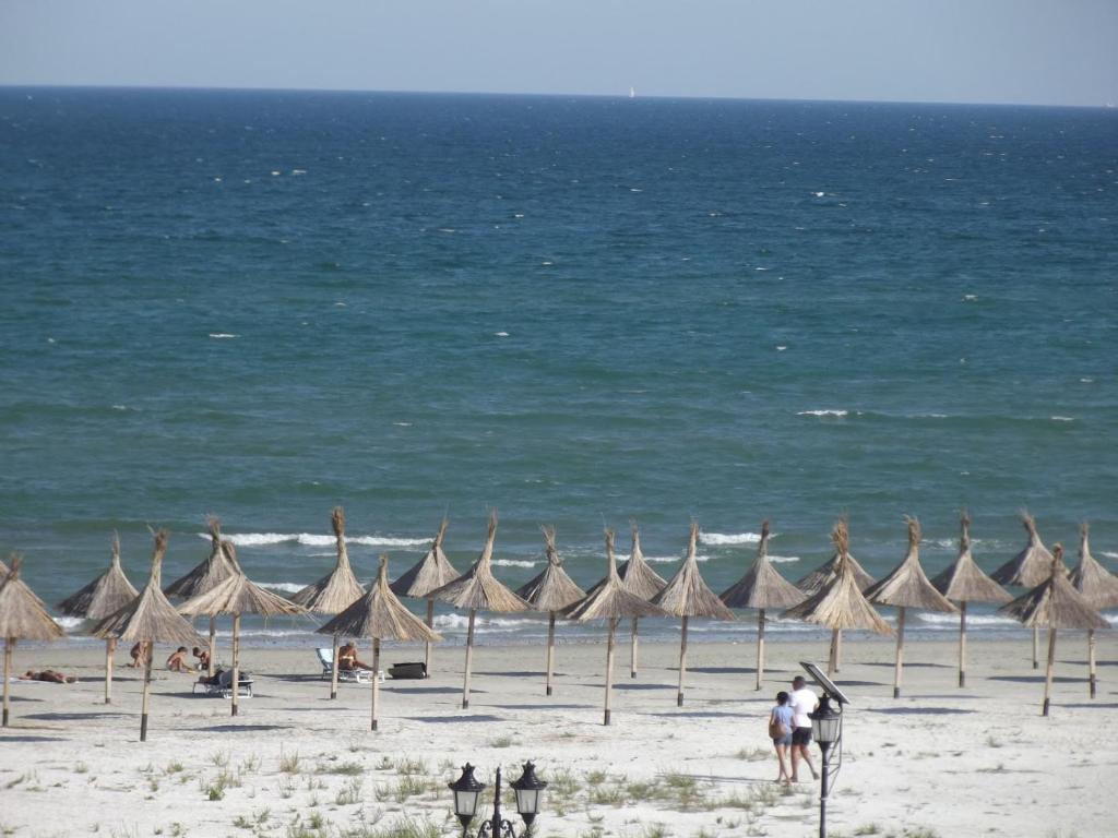 uma praia com guarda-sóis e pessoas na praia em Masha em Mamaia Nord – Năvodari