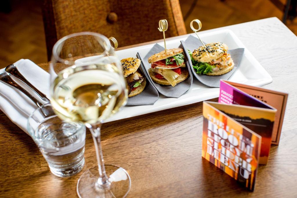 a plate of sandwiches and a glass of wine on a table at Hotel Klaus K in Helsinki