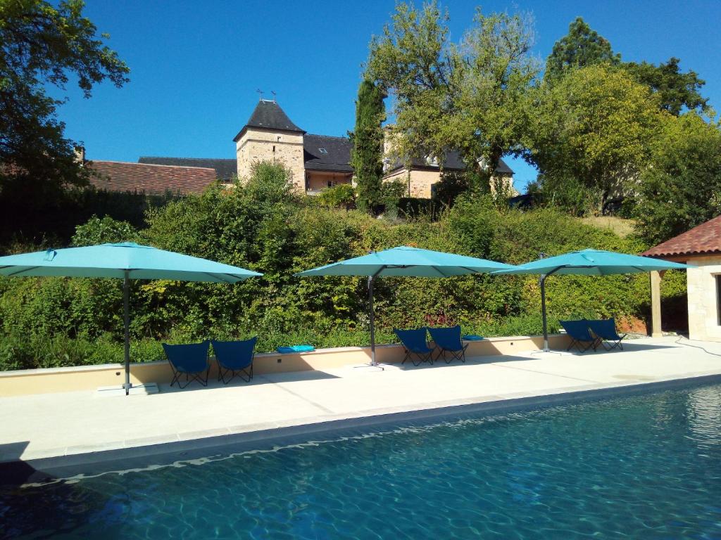 a pool with blue chairs and umbrellas next to at Les Bernardies in Simeyrols