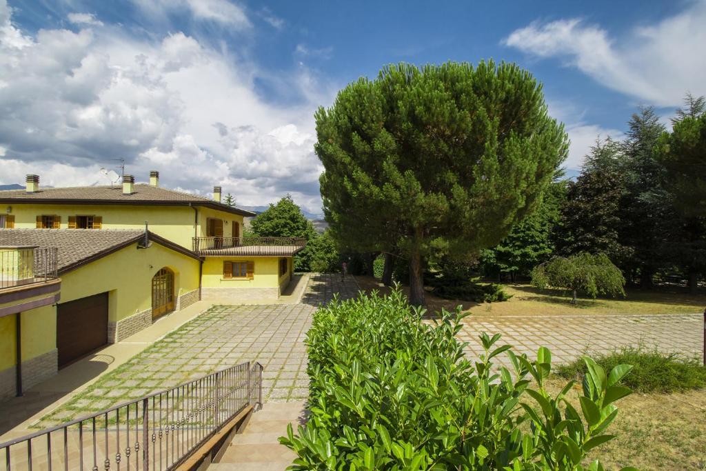 a house with a tree and a walkway at Villa Pina in LʼAquila