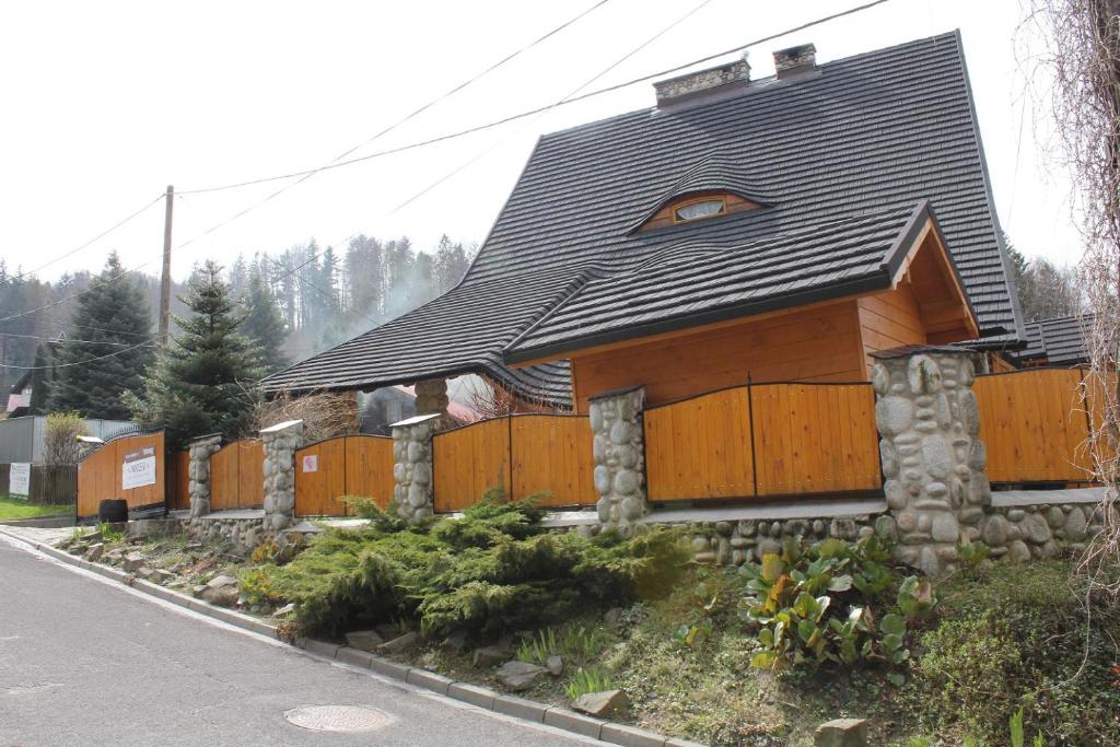 a wooden house with a black roof at Marang Domki i Apartamenty in Szczyrk