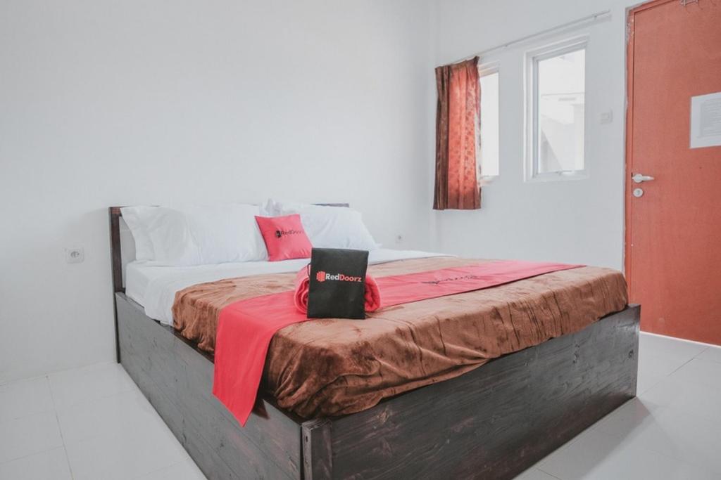 a bedroom with a bed with a red blanket on it at RedDoorz near Gatot Subroto Lampung 2 in Bandar Lampung
