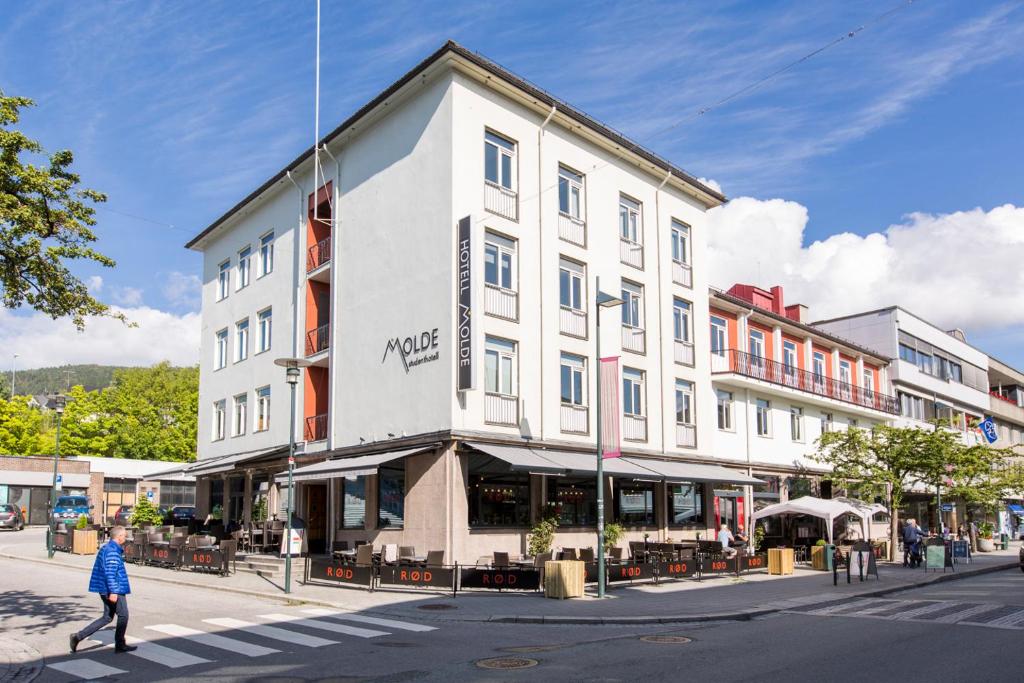 eine Person, die vor einem Gebäude eine Straße überquert in der Unterkunft Hotell Molde in Molde