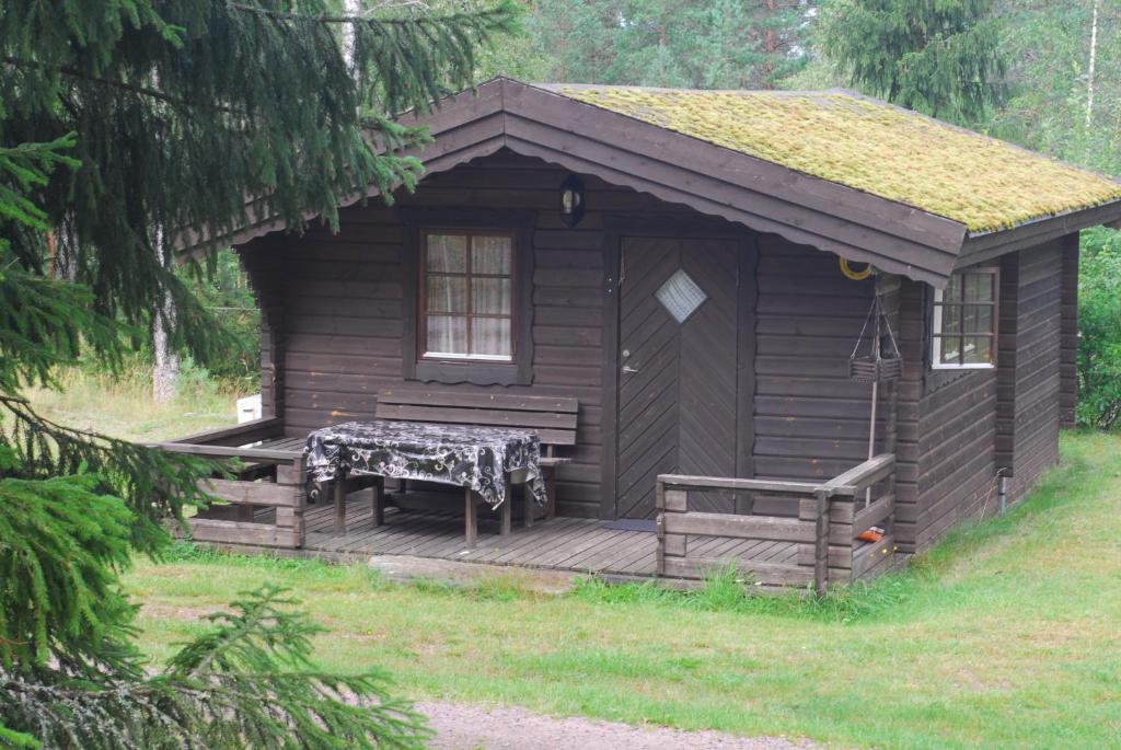 uma pequena cabina com um alpendre e um banco num deque em Lidens Stugby em Vaggeryd