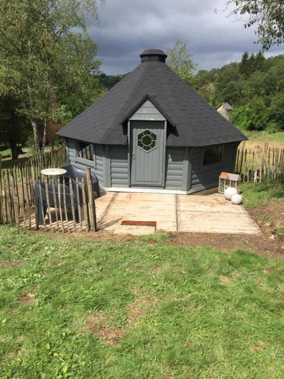 a small house with a black roof and a patio at La cabane de l'Atelier in Bomal