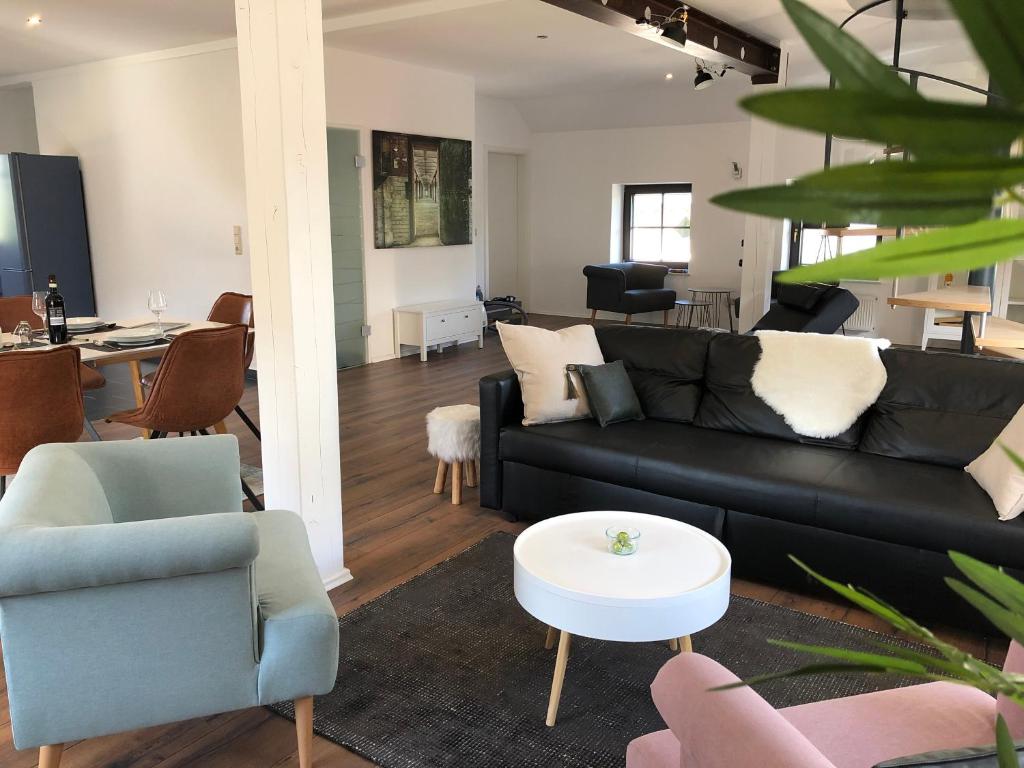 a living room with a black couch and chairs at Landhaus N°3 in Perl