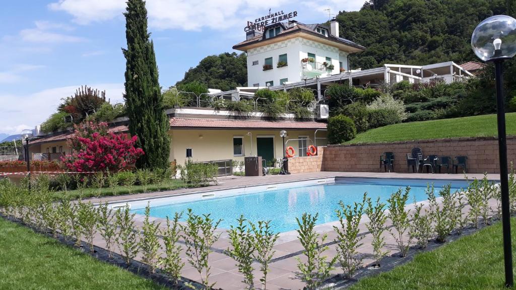 a villa with a swimming pool in front of a house at Hotel Karinhall in Trento