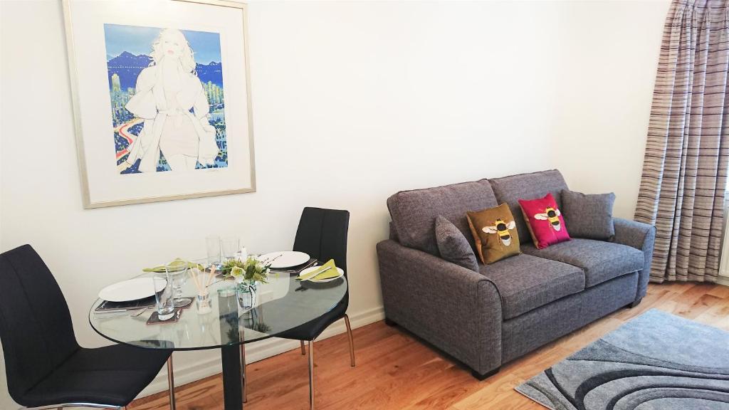 a living room with a couch and a glass table at Violet Bank Apartment West End. in Edinburgh