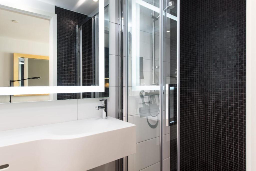 a bathroom with a white sink and a mirror at Thon Hotel Rosenkrantz Oslo in Oslo