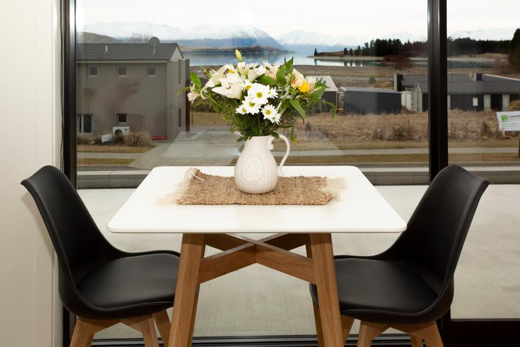 un jarrón de flores sentado en una mesa con dos sillas en Wahi Nui, en Lake Tekapo