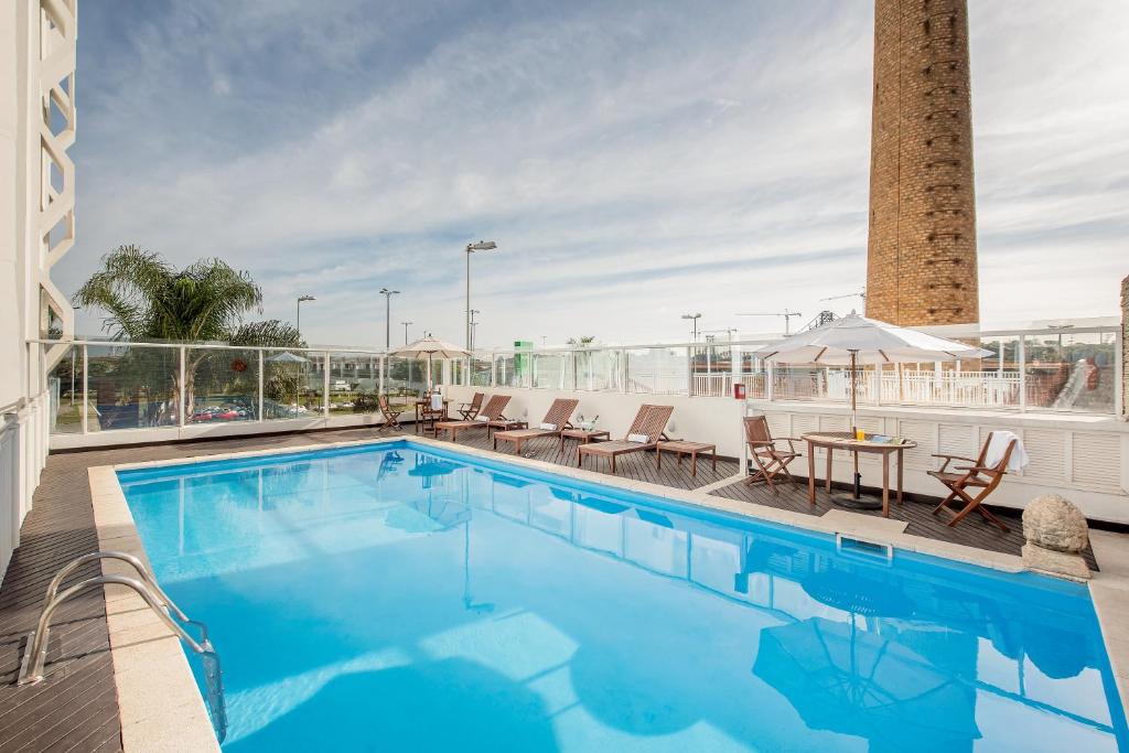 a pool on the roof of a hotel with chairs and a table at Intercity Florianopolis in Florianópolis