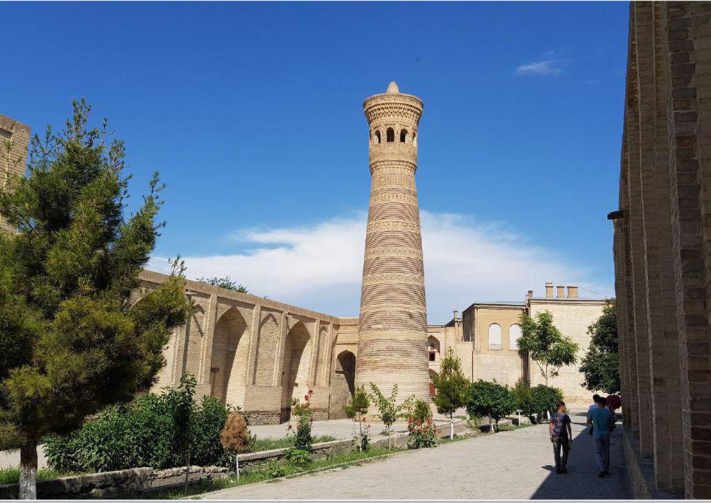 a tall tower in front of a building at Minorai Xurd in Bukhara