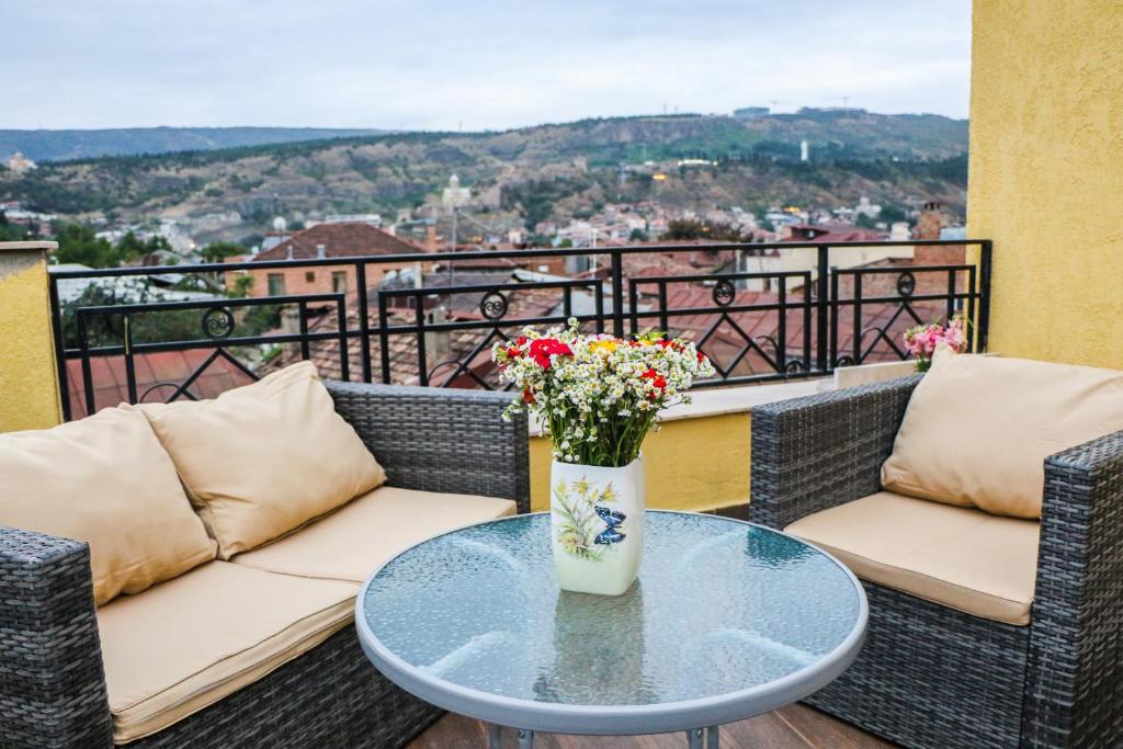una mesa con un jarrón de flores en el balcón en Vincent, en Tiflis