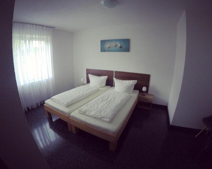 ein Schlafzimmer mit einem großen Bett mit weißer Bettwäsche und einem Fenster in der Unterkunft Gästezimmer Faut in Schorndorf