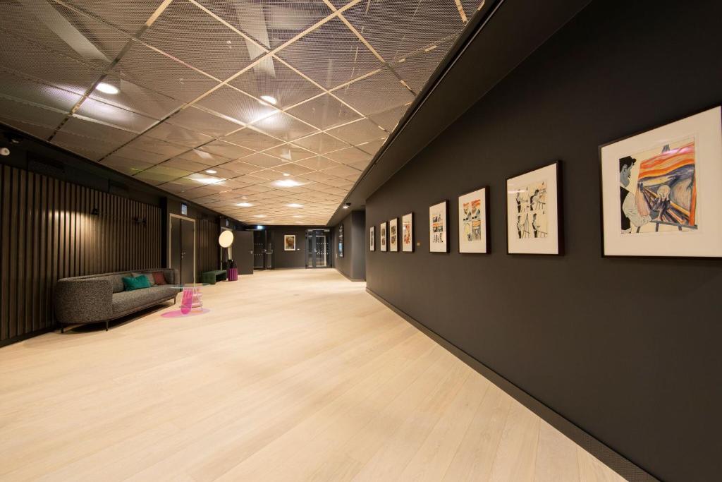 a hallway with paintings on the wall and a couch at Clarion Hotel Oslo in Oslo