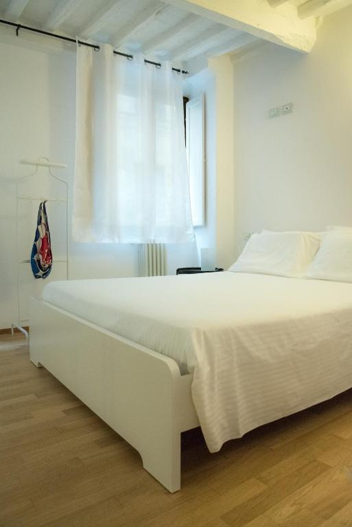 a white bed in a white bedroom with a window at La casa in Camollia in Siena