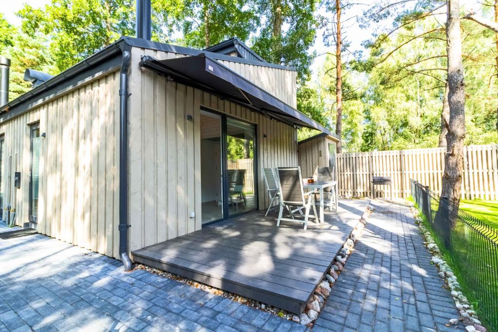 eine Hütte mit einer Terrasse mit einem Stuhl darauf in der Unterkunft Life's a Beach Cottage in Palanga