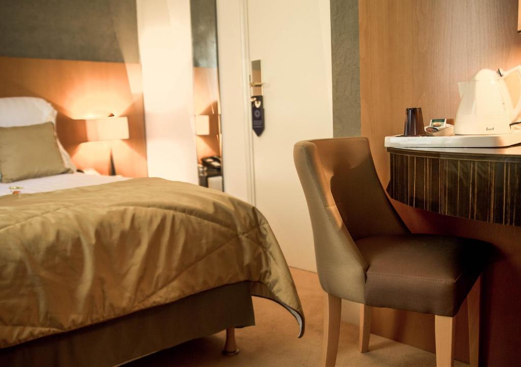 a bedroom with a bed and a chair next to a desk at Hotel Boronali in Paris