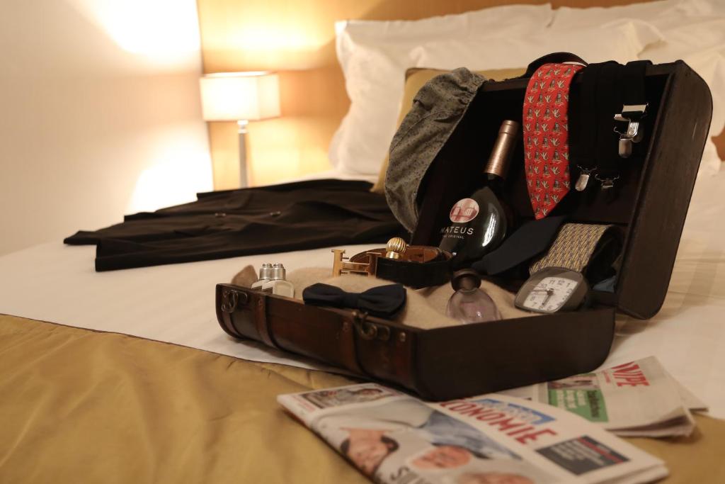 a suitcase is open on a bed with a magazine at Hotel Boronali in Paris