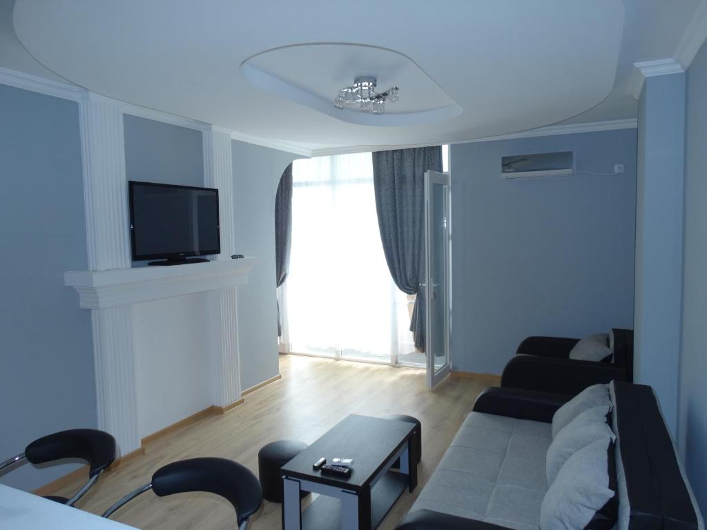 uma sala de estar com um sofá e uma televisão em Apartment White Magnolia em Batumi