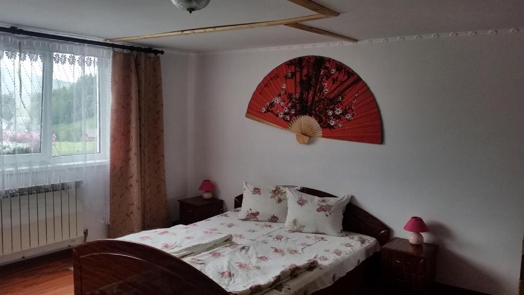 - une chambre avec un lit doté d'une horloge rouge sur le mur dans l'établissement Приватна садиба "Вікторія', à Yasinya