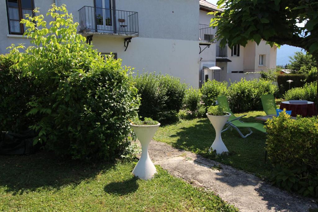 deux vases blancs assis dans l'herbe dans une cour dans l'établissement Les Meublés des Coteaux d'Aix, à Aix-les-Bains