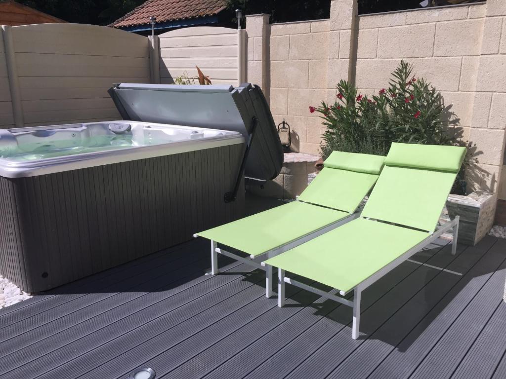 a deck with a hot tub and two chairs and a table at LE COEUR MEDOCAIN in Saint-Vivien-de-Médoc