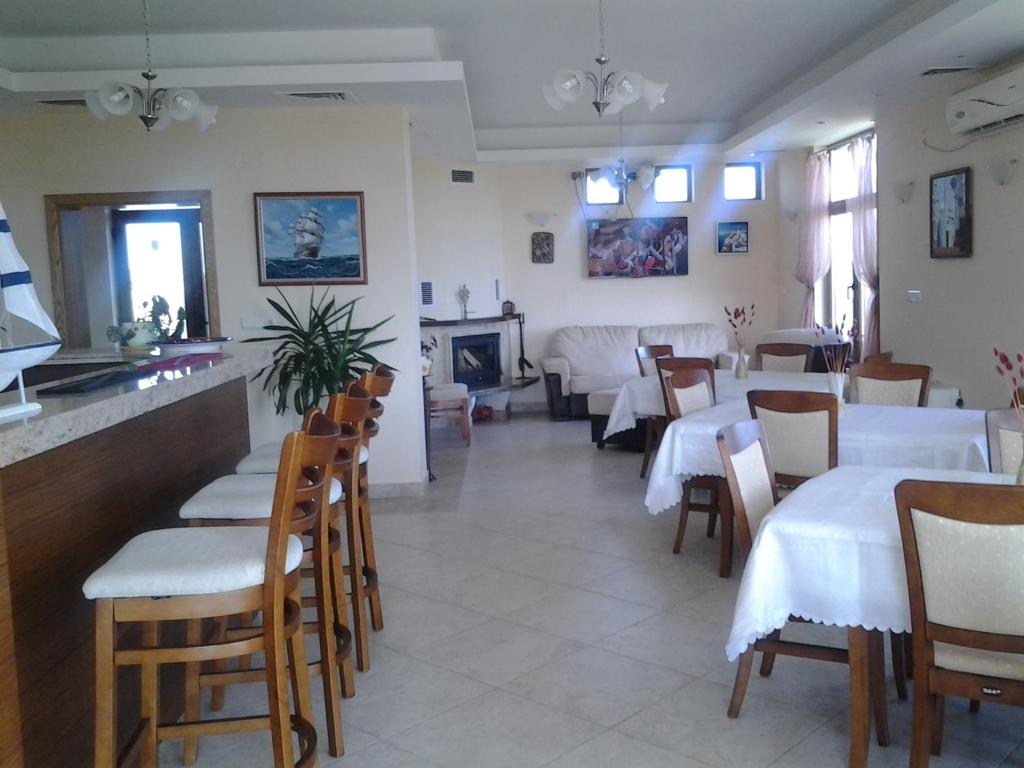 a restaurant with white tables and chairs and a fireplace at Guest House Golden Flake 4km from Bolata beach in Bŭlgarevo
