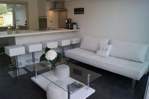 a living room with a white couch and a kitchen at Le Gîte de l'Océan in Lège-Cap-Ferret