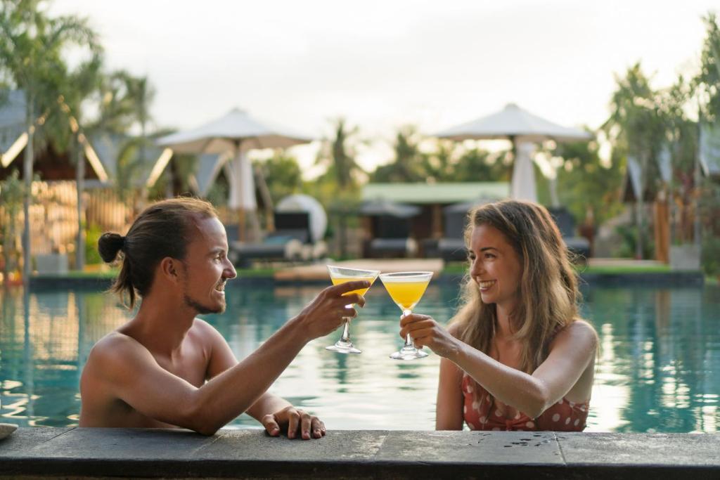 un uomo e una donna che bevono cocktail in piscina di Wah Resort Gili Trawangan a Gili Trawangan