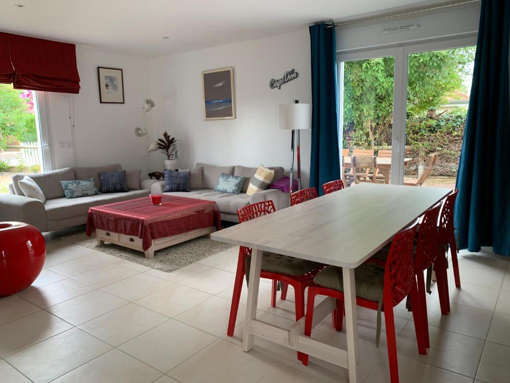 Maison récente à 200m de la plage في Bernières-sur-Mer: غرفة معيشة مع طاولة وكراسي وأريكة