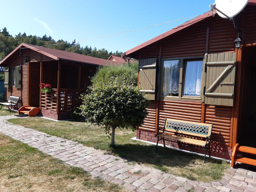 a wooden cabin with a bench in front of it at 2 Bursztyny in Rusinowo