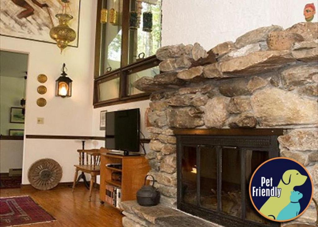 a living room with a stone fireplace with a tv at Perfect secluded 3 bedroom cozy getaway home Hawk Landing in Pittsfield