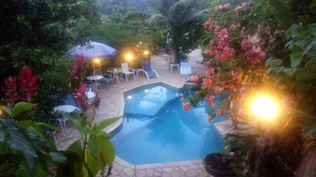una vista aérea de una piscina con sillas y flores en Candy Ilhabela 1, en Ilhabela