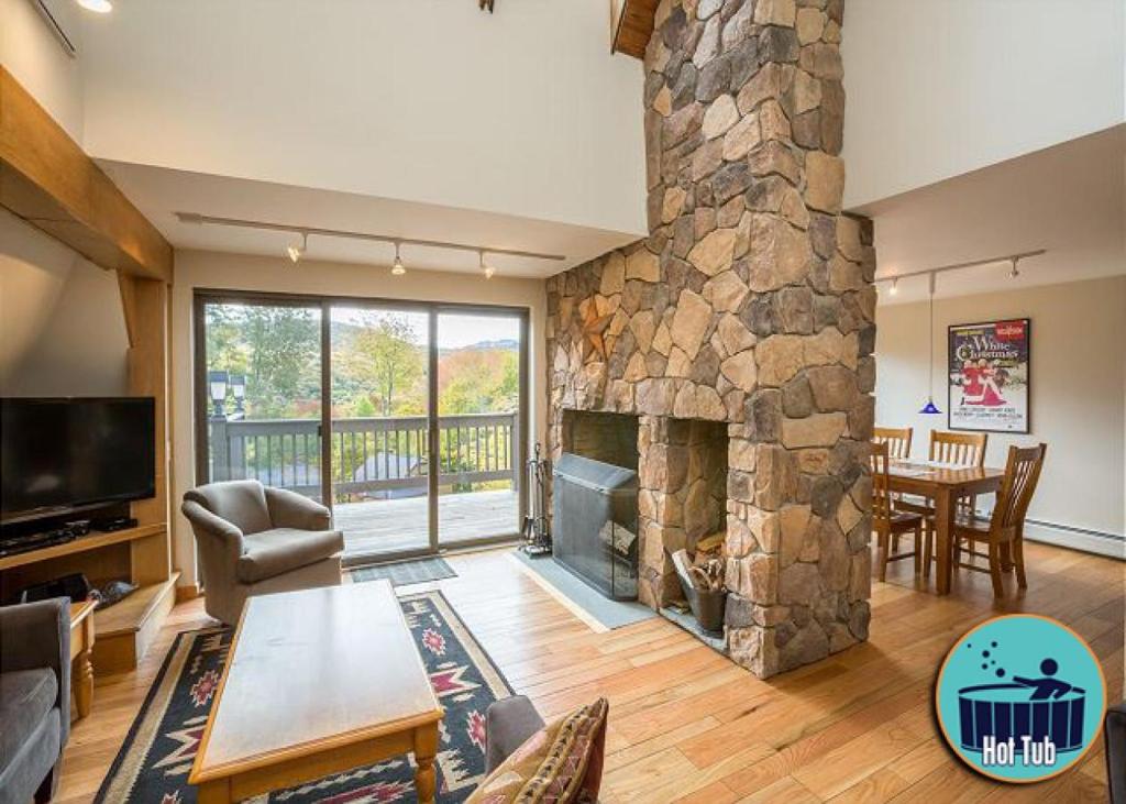 una sala de estar con una gran chimenea de piedra. en Distinctive 4 bedroom townhouse, with outdoor hot tub minutes from the slopes Winterberry 4, en Killington