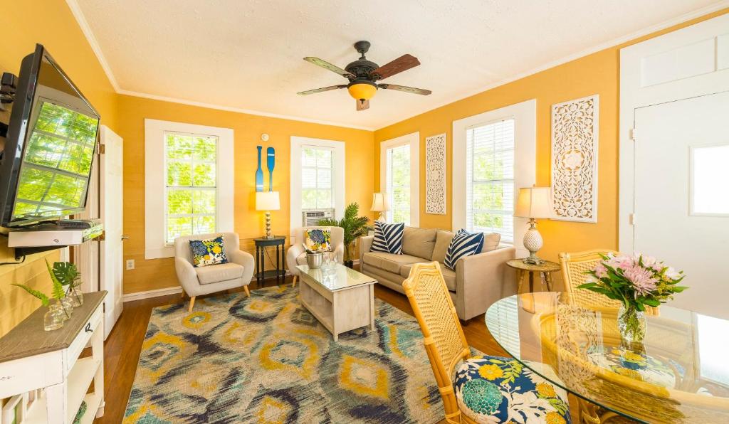 ein Wohnzimmer mit gelben Wänden und einem Deckenventilator in der Unterkunft Rose Lane Villas in Key West